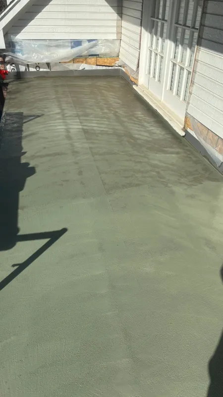 Green coating across a covered balcony floor beside exterior doors