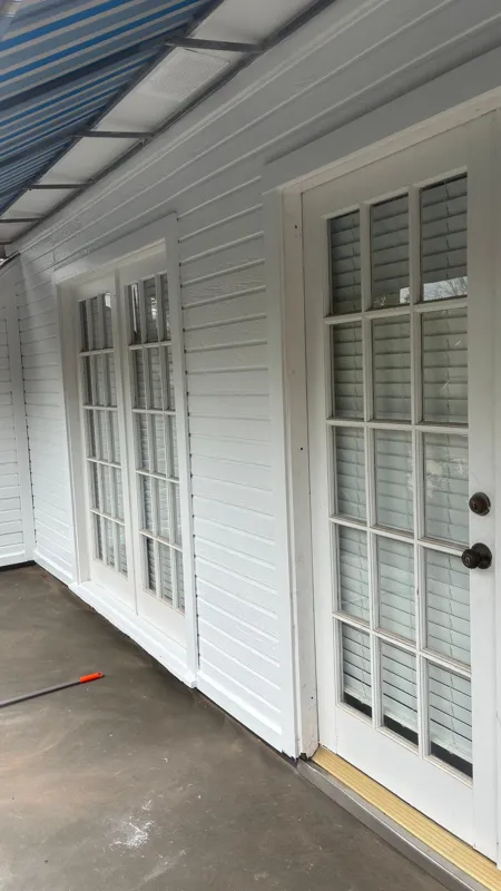 White exterior doors beside a covered balcony surface