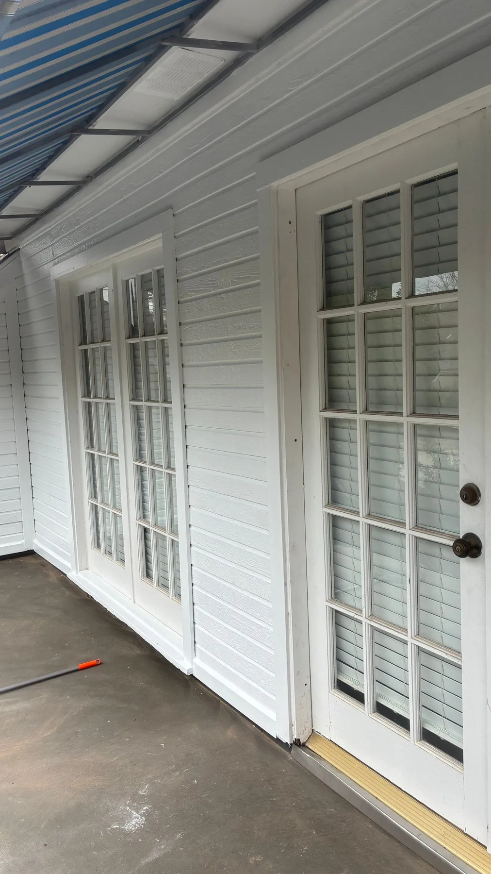 White exterior doors beside a covered balcony surface