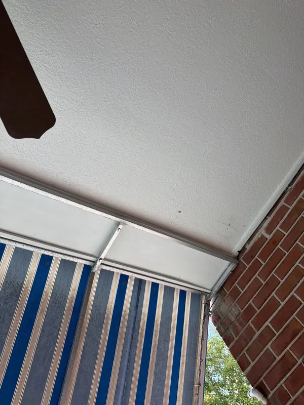 White balcony soffit above railings and the brick wall