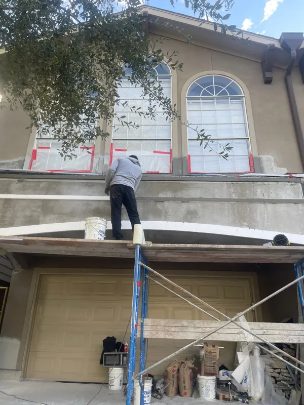 Residential exterior with arched windows above scaffolding