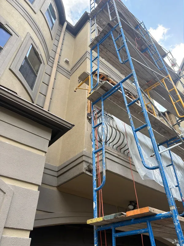Scaffolding reaching the upper-story stucco facade