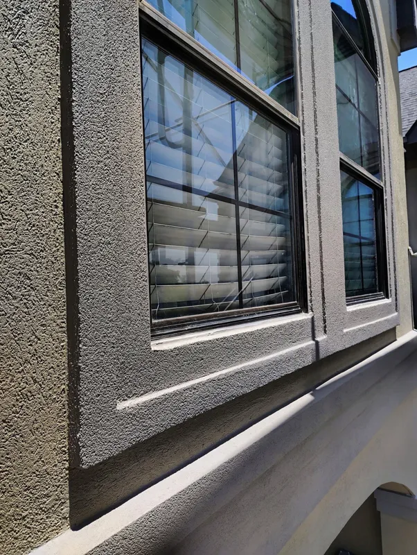 Textured stucco and dark trim surrounding a window
