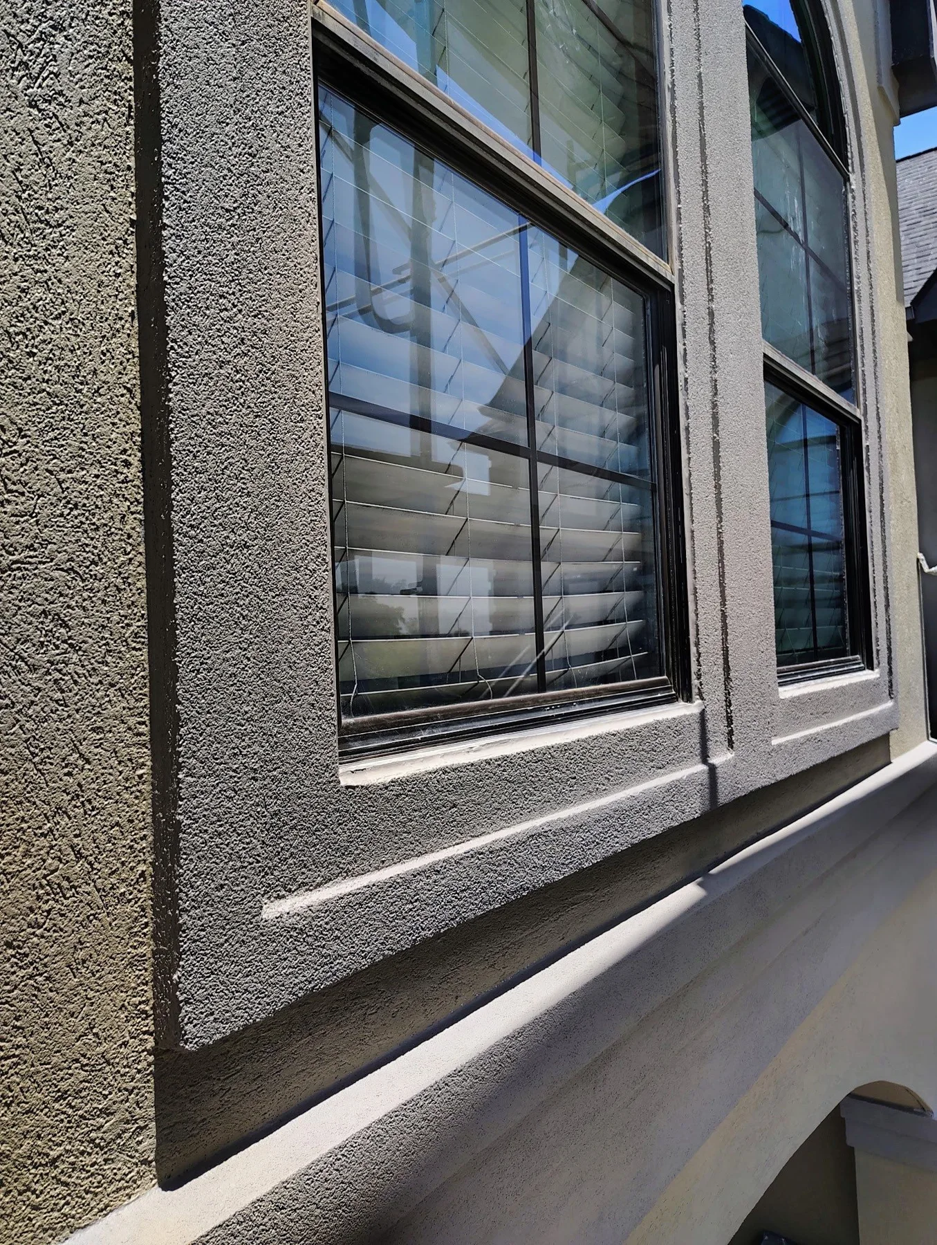 Textured stucco and dark trim surrounding a window