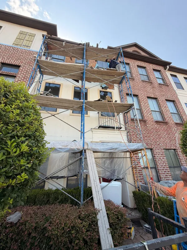 Scaffolding across the front of a brick and stucco townhome