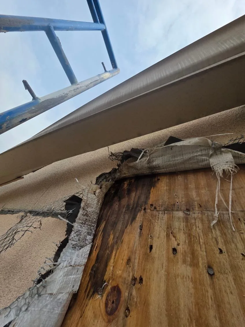 Wood sheathing exposed beneath a horizontal exterior trim