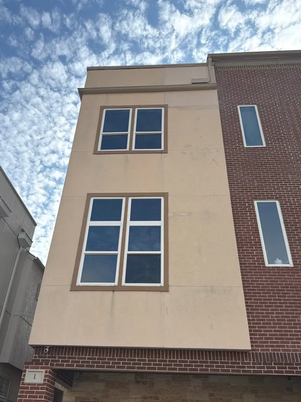 Light stucco and brick townhouse facade with tall windows
