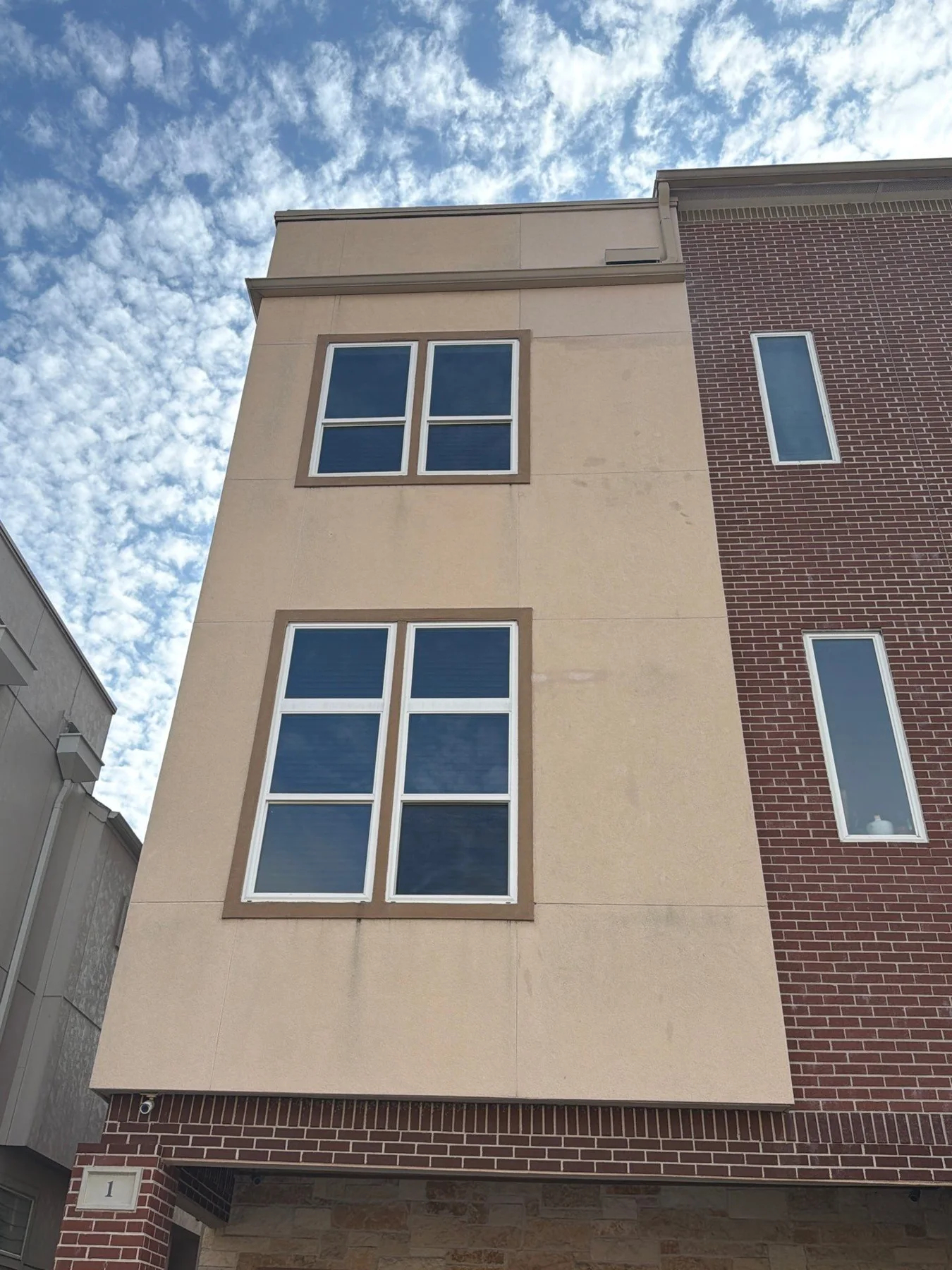 Light stucco and brick townhouse facade with tall windows