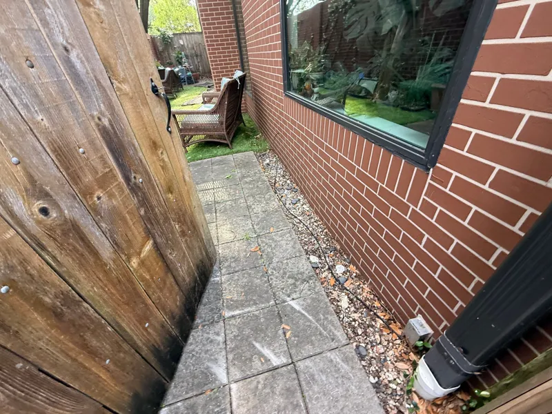 Paved side access beside a brick wall and timber fence