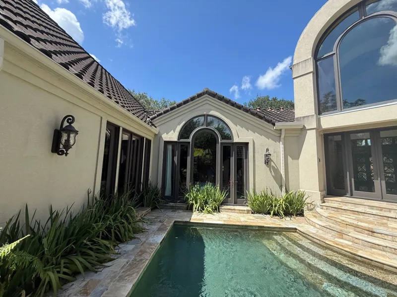 Light stucco walls and arched windows around a pool courtyard