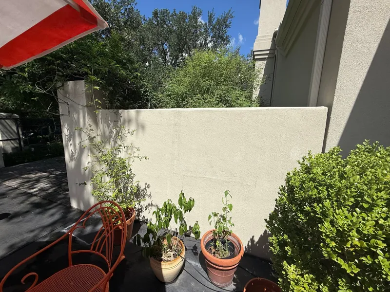 Stucco courtyard wall beside planting and outdoor furniture
