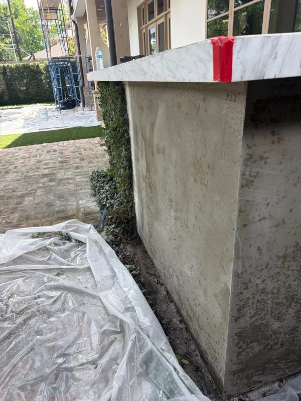 Stucco base coat below a protected window