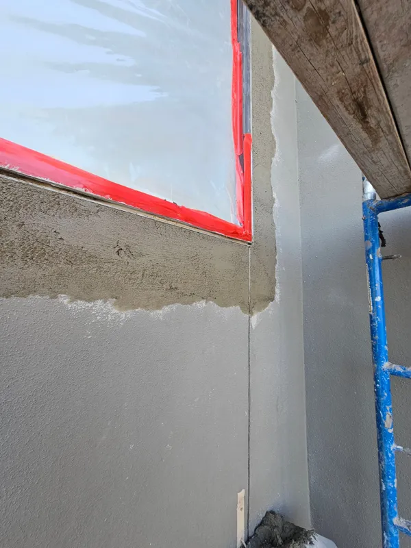 Fresh stucco repair coat around a masked window