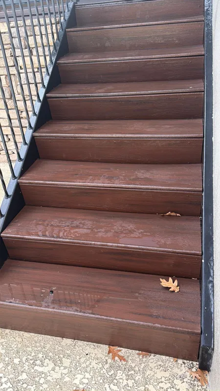Brown outdoor stair treads bordered by dark metal railing