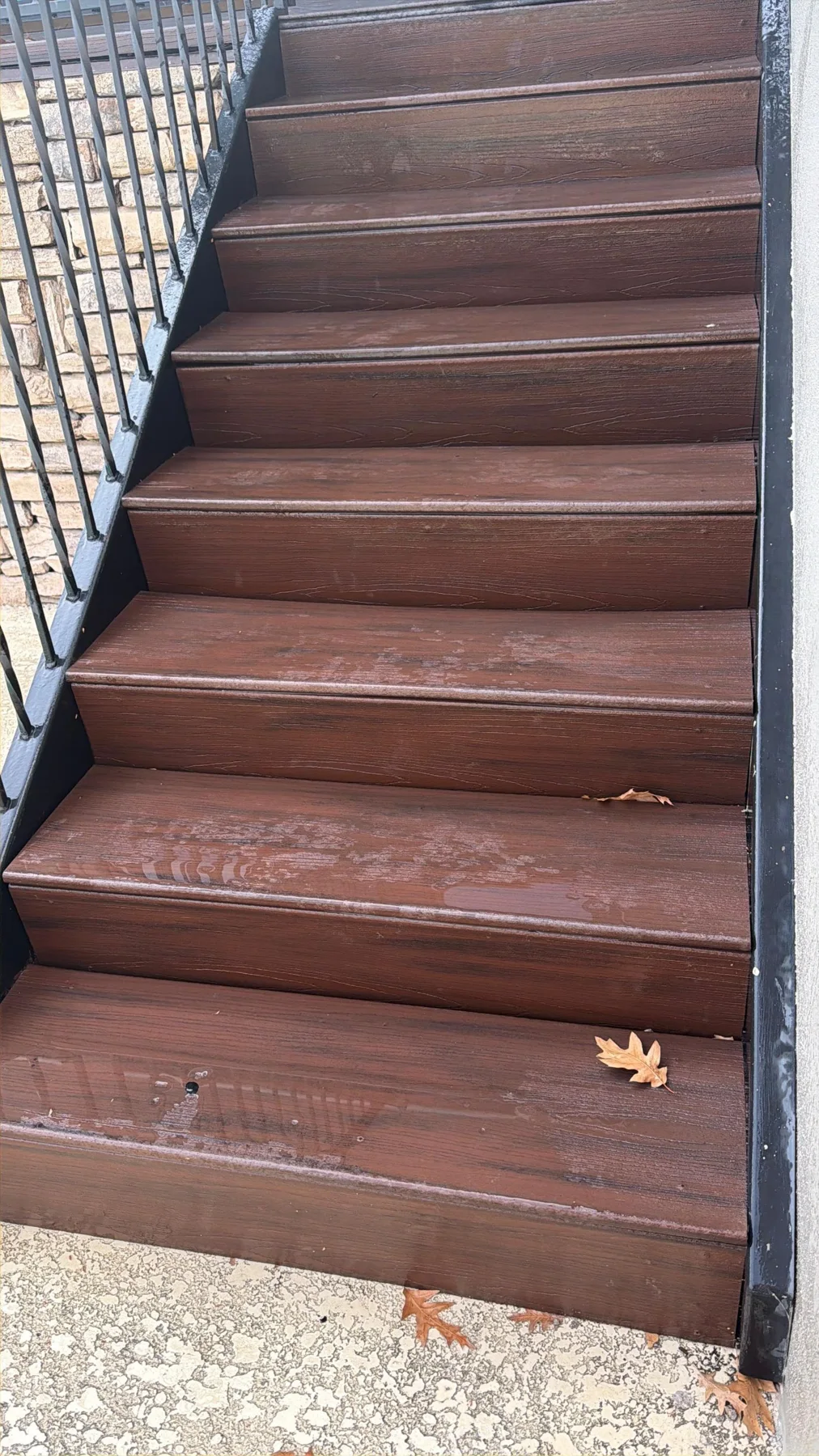 Brown outdoor stair treads bordered by dark metal railing