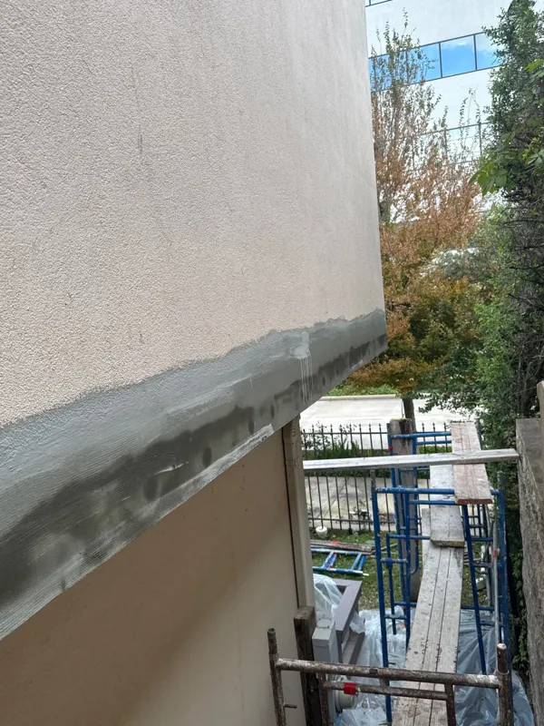Stucco repair coat across the wall below a window