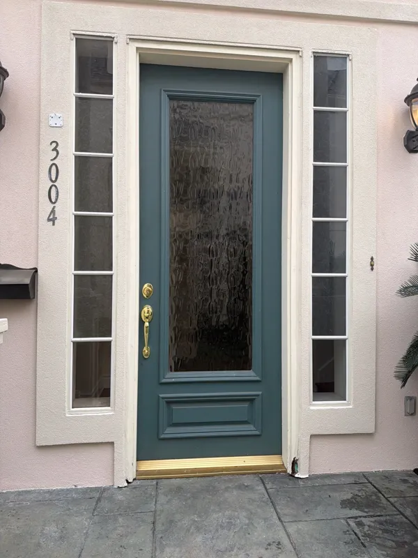 Entry door with narrow windows and stucco trim