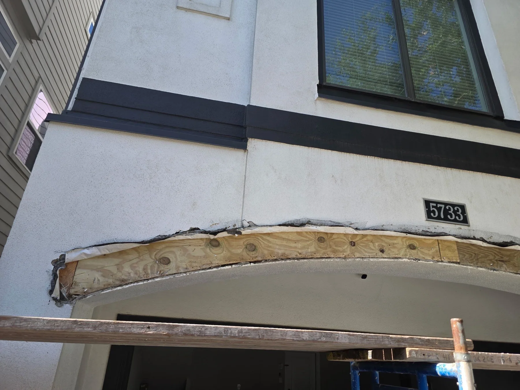 Opened and cracked stucco above an arched garage opening