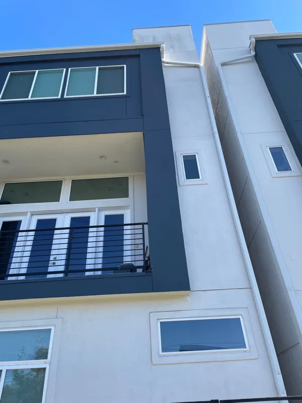 Modern exterior with dark balcony railing and light stucco