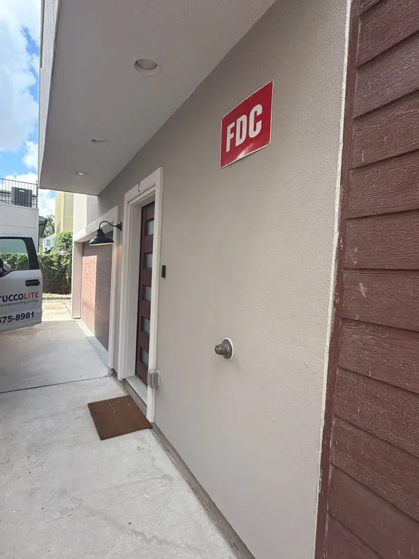 Stucco walls and soffit along a covered exterior passage