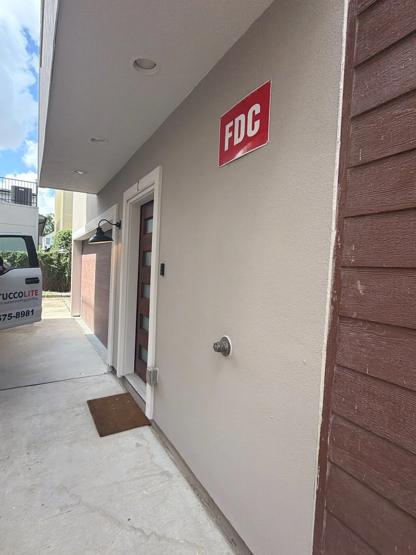 Stucco walls and soffit along a covered exterior passage