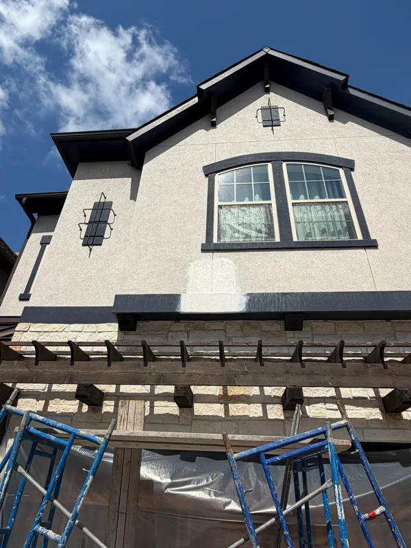 Stucco facade with arched window and dark roof trim