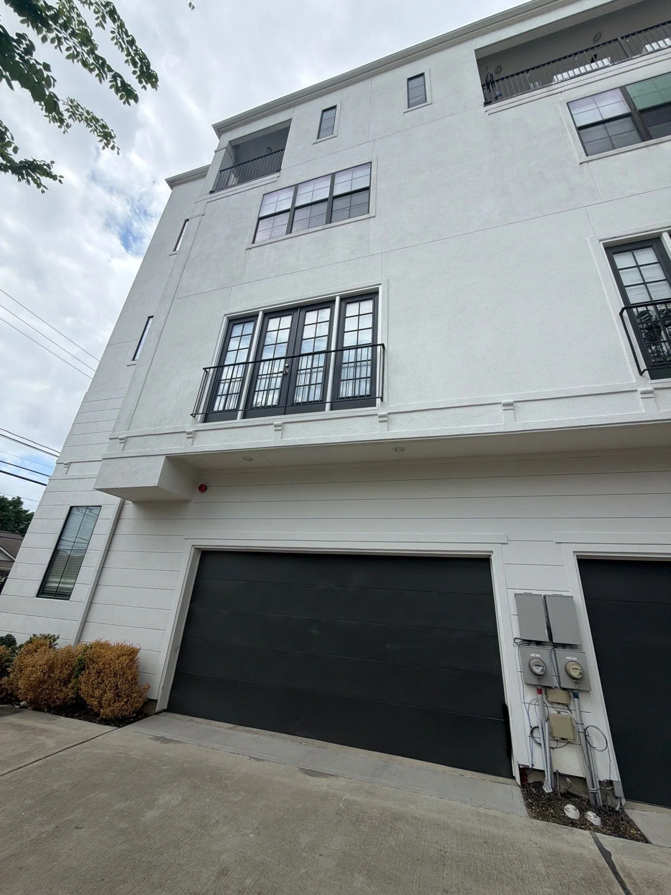 Three-story white townhome and garage in a later project view