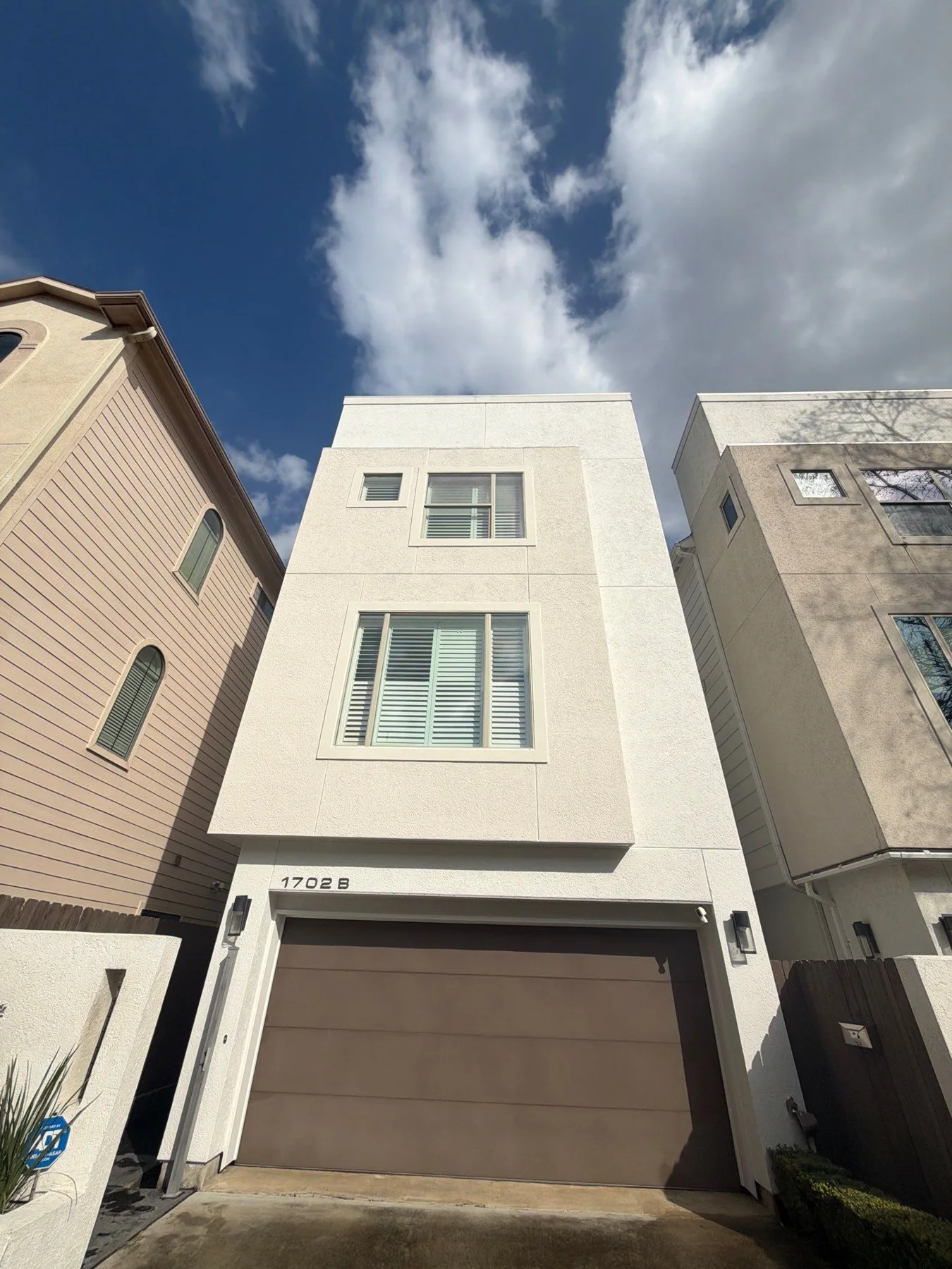 Light-colored stucco townhouse with a dark garage door