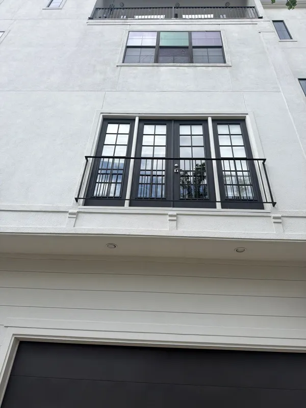 White townhome exterior with black-framed windows and railing