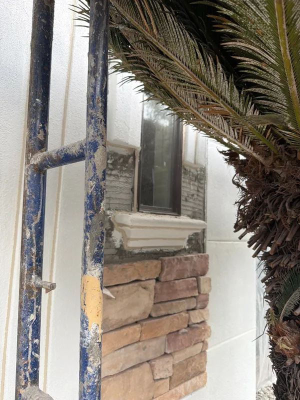 Stone and stucco detailing beneath a window