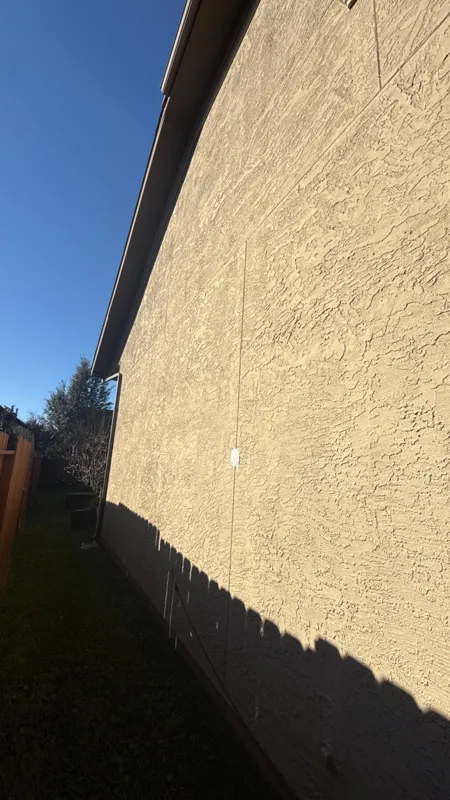 Stucco wall edge beneath a roof overhang