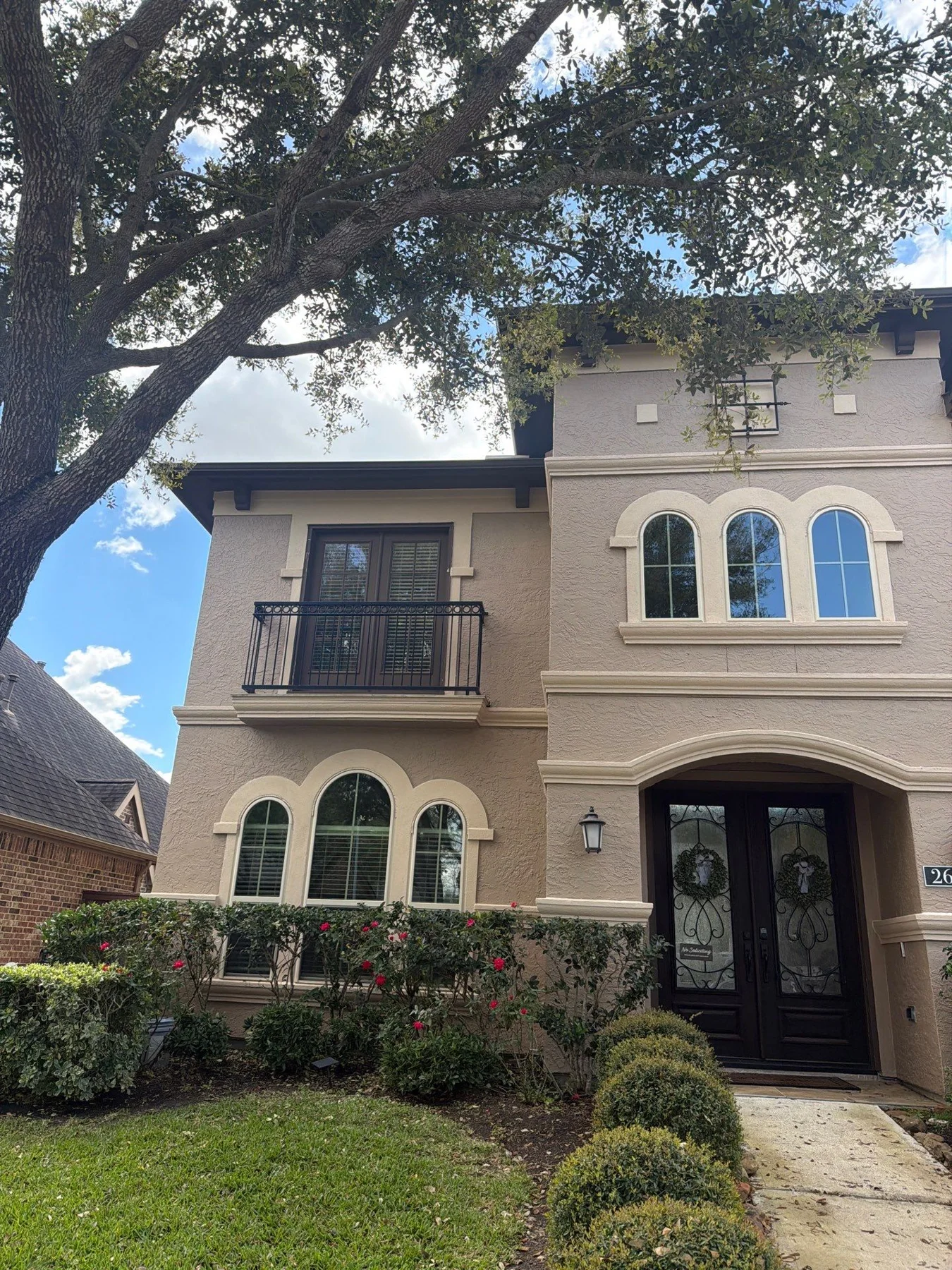 Two-story stucco home with arched entry and landscaping