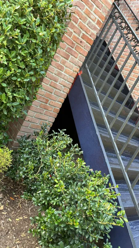 Stair and railing detail beside a brick wall