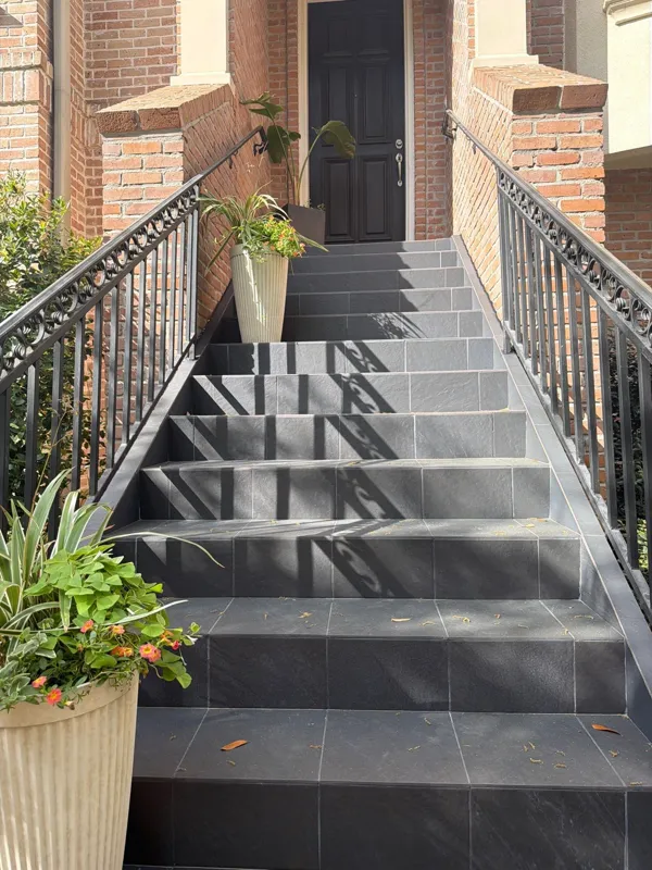 Gray finished stair treads and dark railings leading to an exterior door