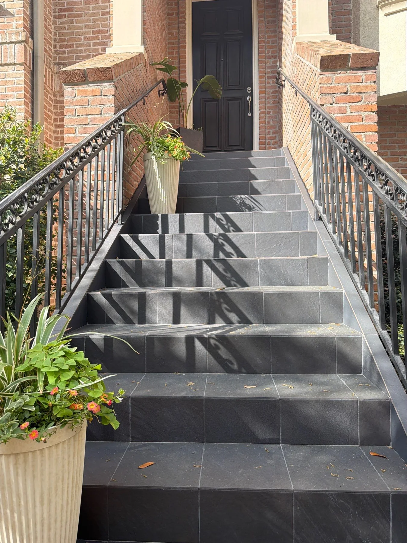 Gray finished stair treads and dark railings leading to an exterior door