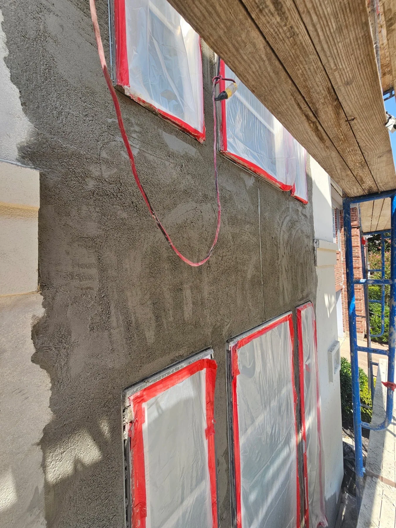 Stucco base coat around masked windows during exterior work